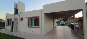 a white building with a car parked in a driveway at Comoda quinta en El Pato in El Pato