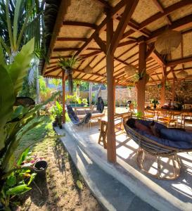 a patio with a wooden pavilion with chairs and tables at Elisa Hostel in Kuta Lombok