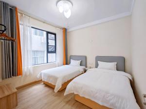 Dos camas en una habitación con ventana. en A&G Apartment, en Zhangjiajie