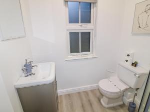 a bathroom with a toilet and a sink and a window at Two in Peterborough