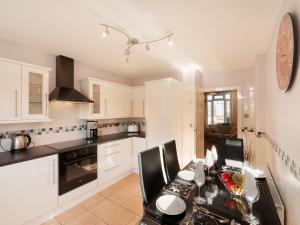 a kitchen with white cabinets and a table with chairs at Two Beaches in Paignton