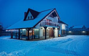 a house covered in snow at night with lights at Pensiunea Ursa in Bistriţa Bîrgăului