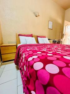 a bedroom with a pink comforter on a bed at Hôtel Saint Thomas in Lomé