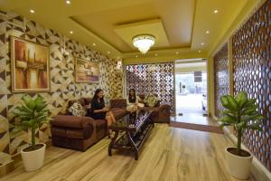 two women sitting on couches in a living room at FabHotel Red Rose - Nr IIT Guwahati in Amingaon