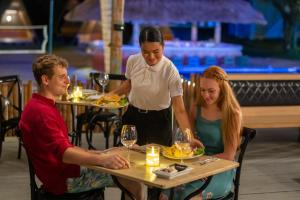 a woman offering a man a plate of food at a table at Slumber Resort Koh Chang in Ko Chang