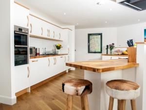 a kitchen with a wooden table and two stools at Strathspey Lodge in Duthil