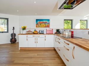 a kitchen with white cabinets and a wooden counter top at Strathspey Lodge in Duthil +18 photos