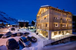 a building with cars parked in a parking lot at Hotel Larice in Livigno