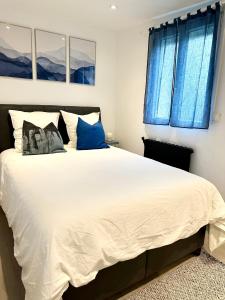 a bedroom with a large white bed with blue windows at Cocon tout confort à 25 min de Paris in Sevran