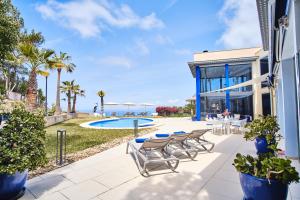 eine Terrasse mit Tischen und Stühlen sowie einem Pool in der Unterkunft Villa Bay Blue in Llucmajor
