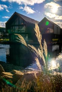 a house on the water with grass in the foreground at Termy Karkonosze Resort & Spa koło Karpacza in Staniszów