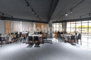 a dining room with tables and chairs and windows at Cozy 2 Br In Ciudad Del Este in Puerto Presidente Franco