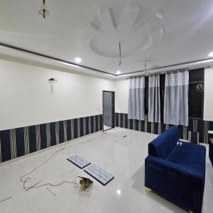 a living room with a blue couch and a drawing on the wall at Hotel Indra in Jaipur