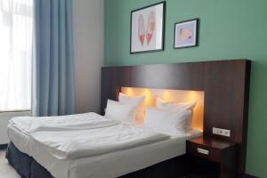 a bedroom with a bed with white sheets and pillows at Garner Hotel Hamburg - Graf Moltke by IHG in Hamburg