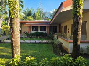 a house with a yard with palm trees in front of it at Marianita's cottages in Mambajao