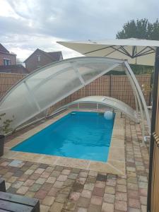 een zwembad met een parasol erover bij Loft envie deux in Rivery