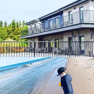 a young boy walking on the beach in front of a building at Palanga INN in Palanga