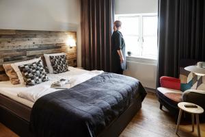 a woman standing in a bedroom looking out the window at Haraldskær Sinatur Hotel & Konference in Vejle