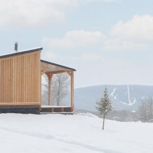 un edificio en la nieve con un árbol en el primer plano en Huttopia Berkshires, en Hancock