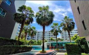 Una vista de un edificio desde un patio con palmeras. en Pool View Cozy 1BR Great Value Stay near BTS, en Amphoe Phra Khanong