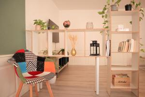a living room with a chair and a table and shelves at Urban Green Spirit - Centre historique, familial in Mulhouse