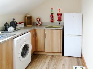a kitchen with a washer and a white refrigerator at Ysgubor Uchaf - 29517 in Fairbourne