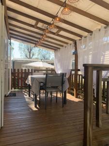 een terras met een tafel en stoelen op een dek bij Au Petit Bonheur in Vias