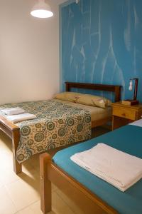 a bedroom with two beds and a blue wall at Apart Hotel Bell in San Fernando del Valle de Catamarca