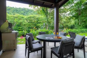 a patio with a table and chairs with a view at Casa Selva Tica 6 bdr pool golf view in Los Suenos in Herradura