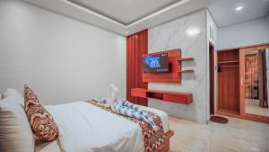 a bedroom with a bed and a tv on a wall at Villa Griya Anyar Ubud in Ubud