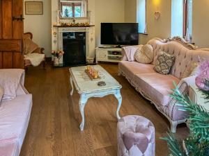 a living room with pink couches and a coffee table at The Old Gatehouse in Heacham