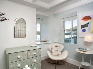 a white room with a chair and a dresser at The Lookout in Polruan +11 photos