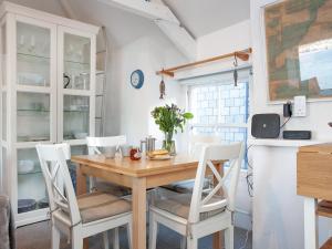 a dining room with a wooden table and white chairs at The Lookout in Polruan