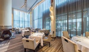 a restaurant with tables and chairs and large windows at InterContinental Johannesburg OR Tambo Airport Hotel by IHG in Kempton Park