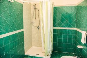 a green tiled bathroom with a shower and a toilet at Hotel Regina del Mare in Ischia
