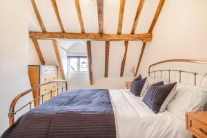 a bedroom with a bed with white sheets at Quaint Cottage by the Castle in Kenilworth
