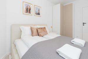 ein weißes Schlafzimmer mit einem großen weißen Bett mit zwei Kissen in der Unterkunft Piastowska 30 Garden Free Parking by Renters Prestige in Przymorze + 17 Fotos
