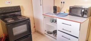 a small kitchen with a stove and a microwave at The Oval House in Otse