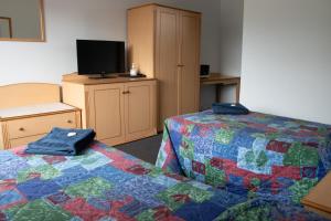 ein Hotelzimmer mit zwei Betten und einem Fernseher in der Unterkunft Sportsmans Arms Hotel Motel Deniliquin in Deniliquin + 8 Fotos