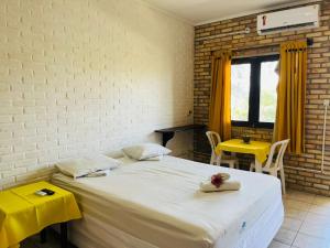 Un dormitorio con una gran cama blanca y una mesa amarilla en Hotel das Falésias Praia das Fontes, en Beberibe 15 fotos más