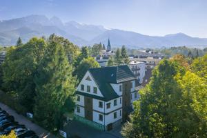 a white house with a green roof and trees at Villa Jarosta Premium & SPA in Zakopane