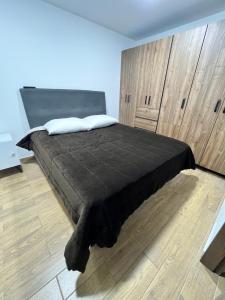 1 dormitorio con cama negra y pared de madera en Moderno apartamento frente a viva mall, en Tunja