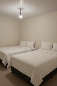 two beds in a room with white walls at A Casa Paradisiaca l Luxo Piscina Super Hiper Quente 60 Graus Aquecimento Elétrico e Piscina Enorme com Roupa de Cama e Banho in Caldas Novas