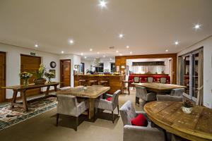 a living room with tables and chairs and a kitchen at L.A.H. Hostellerie in Campos do Jordão