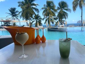a table with vases and a drink on a table near a pool at KAY TI'TINY T2 NEUF de STANDING MER & PISCINE in Le Diamant