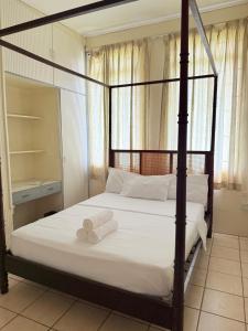 a bedroom with a four poster bed with two towels at Bungles Ungalow in Castries