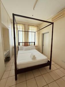 a bedroom with a canopy bed with white sheets at Bungles Ungalow in Castries +4 photos