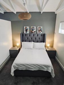 een slaapkamer met een groot wit bed met twee lampen bij Blouberg Rise Cottage in Kaapstad