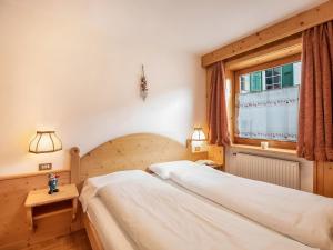 a bedroom with two beds and a window at Ciasa Lino Aloch in Pozza di Fassa