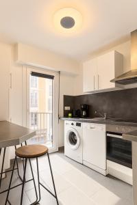 a kitchen with a washing machine and a table at Appartement confortable avec balcon - Proche Gare Riquier SNCF in Nice